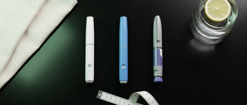 Três canetas injetoras de medicamentos GLP-1 sobre superfície escura com fita métrica — representação visual da comparação entre Ozempic, Wegovy e Mounjaro